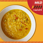 Yellow soup in a white bowl on an orange background with a mild spice level indicator.
